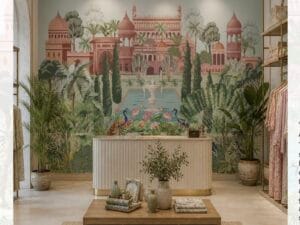 Luxury heritage mural wallpaper featuring a royal Indian palace, lush tropical gardens, peacocks, lotus pond, and classical architecture in soft pastel tones.