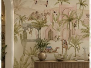 Tropical mural wallpaper featuring palm trees, desert architecture, camels, birds, and lush greenery in soft pastel tones.