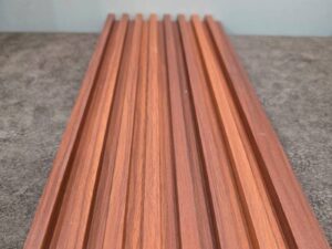 Reddish-brown wood-look fluted wall panel displayed on a wooden table