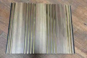 Grey wood-texture fluted wall panel with multiple vertical grooves and decorative gold metallic strips.