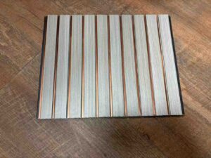 Light grey wood-texture fluted wall panel with vertical grooves and copper-gold decorative strips.