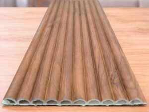 Wood finish fluted wall panel with vertical grooves displayed on a wooden surface.