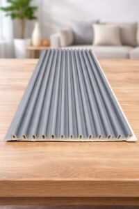 Grey fluted wall panel with vertical grooves displayed on a wooden table in a modern living room.