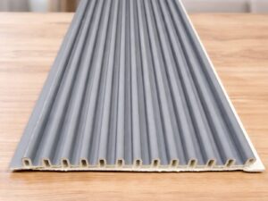 Grey fluted wall panel with vertical grooves displayed on a wooden table in a modern living room.