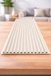 White fluted wall panel with vertical linear grooves displayed on a wooden surface in a modern living room.